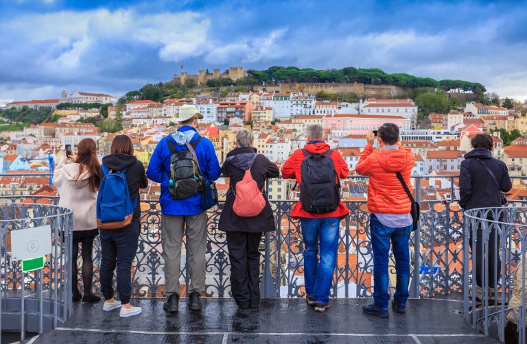 Group of tourists watching the cityscape of Lisbon and taking pictures of Sao Jorge castle in Portugal